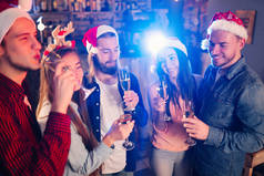 朋友们一起庆祝新年。 爱喝鸡尾酒派对的朋友的肖像。 年轻人笑了。 一群戴着圣诞礼帽的漂亮年轻人. 模糊的背景.