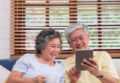 亚洲老年夫妇使用桌算和喝咖啡坐在客厅的卫生间。.