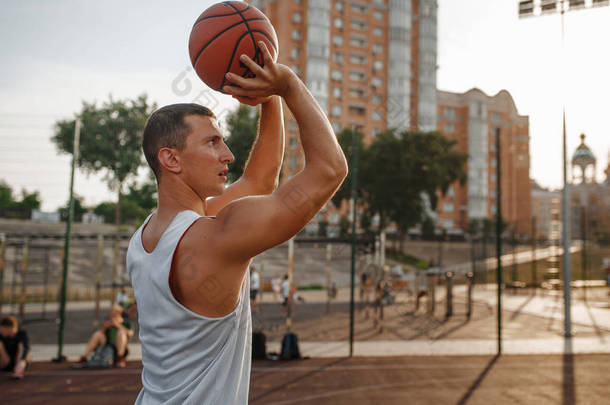 篮球运动员在室外场地抛球. 男子运动员在街头篮球训练中的运动服射击、跳跃动作