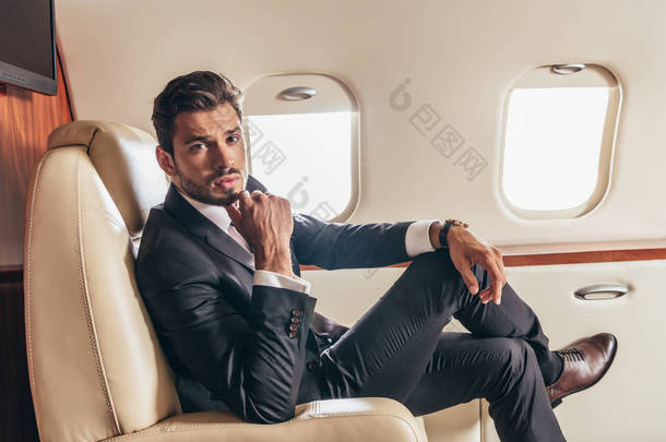 穿着西服的英俊商人在私人飞机上看着相机 
