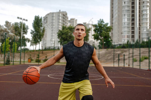 球在室外球场上运动的篮球运动员. 男子运动员在街头篮球训练中的运动服射击、跳跃动作