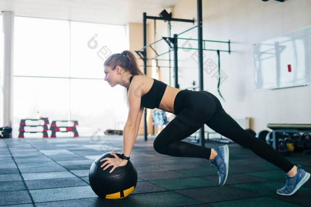 有运动魅力的女人靠药物球做运动,抬腿向上.职能培训概念
