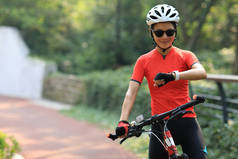 亚洲女骑车人在阳光明媚的白天骑自行车时看着聪明的女人
