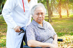 医生帮助和护理亚洲老年或老年老太太女病人坐在轮椅在公园在护理医院病房：健康强医疗理念