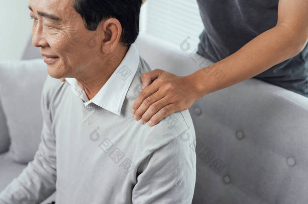 亚洲老人肩痛，坐在坐在马肩上，儿子按摩父亲的<strong>肩膀</strong>.