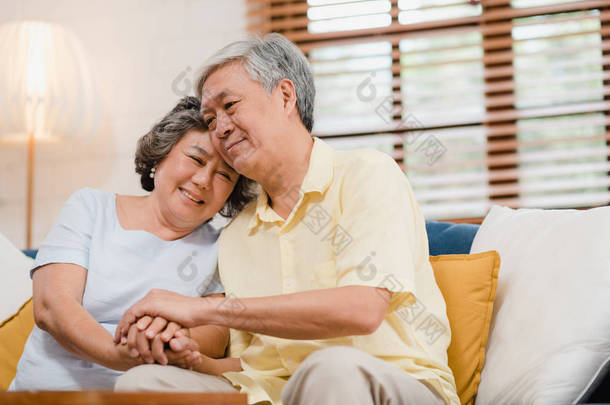 亚裔老夫妇手牵手，一边在客厅里，夫妻俩心情愉快，互相支持，躺在家里的病床上。生活方式 家庭老年家庭概念.
