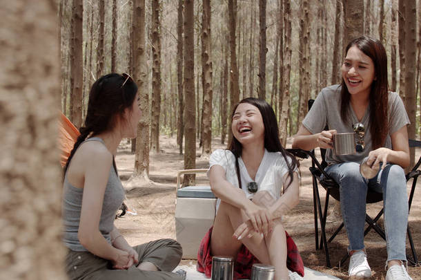 一群年轻的亚洲朋友在森林里露营或野餐，少女在帐篷前<strong>享受</strong>着片刻的交谈。女人在夏天的假期里做冒险活动和旅行.