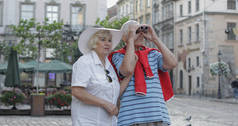 老年男女游客走在市中心，看着望远镜