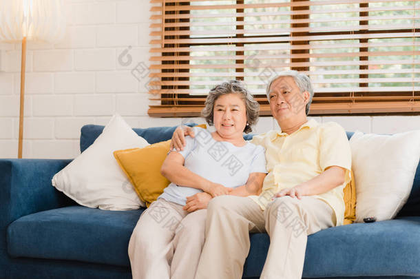 在家里客厅里看电视的一对亚洲老<strong>夫妻</strong>，在家里放松的时候，躺在沙发上享受爱情的时刻。享受家庭幸福的<strong>生活</strong>方式.