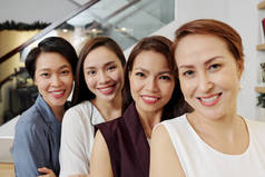 亚洲年轻成功女商人在办公室里排成一排,对着镜头微笑的肖像