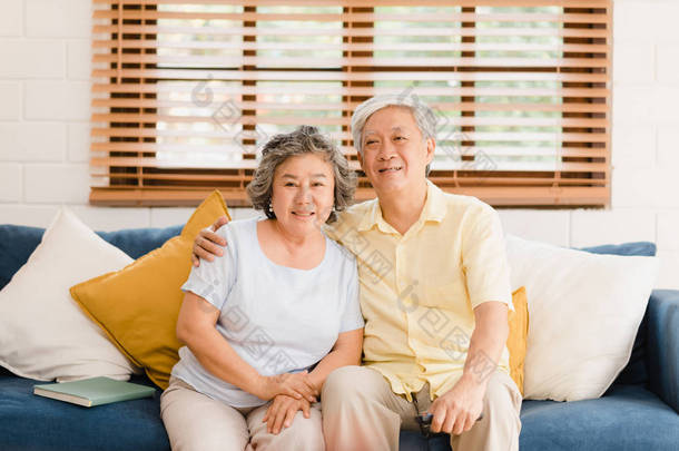 在家里客厅里看电视的一对亚洲老夫妻，在家里放松的时候，躺在沙发上享受爱情的时刻。享受家庭幸福的<strong>生活</strong>方式.