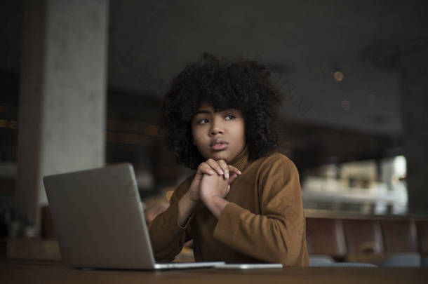 一个年轻的工人，一个<strong>实习生</strong>，一个非裔美国人，为笔记本电脑工作，利用互联网资源，社交网络搜索信息。在办公室的计算机工作