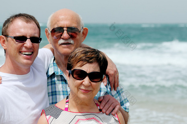 成人的儿子与他的父母在沙滩上散步