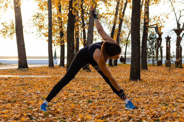 俄罗斯哈巴罗夫斯克 - <strong>2018</strong>年10月7日：一个穿着运动服的漂亮女人在自然风光和阿穆尔河上做运动，<strong>喜</strong>欢体操，揉着腿。活跃的年轻女孩 en