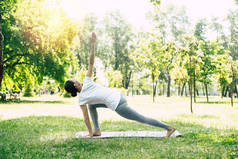 瑜伽为健康和强壮的身体。年轻美丽的女人在公园户外做瑜伽。女孩在伸展和冥想.