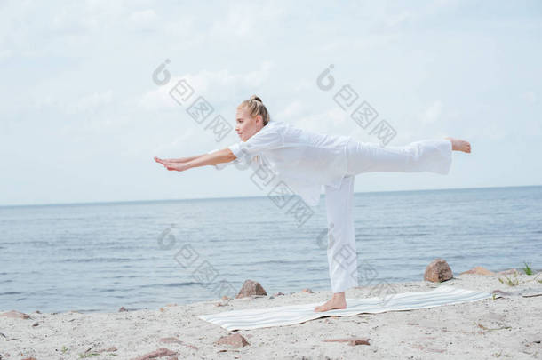 迷人的金发女郎练习瑜伽瑜伽瑜伽在瑜伽垫近海 