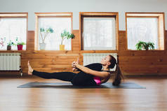 年轻的瑜伽运动女人工作，热身使用瑜伽带，躺在瑜伽仰卧 Padangushthasana，一条腿抬起锻炼、 倾斜的变化的扩展手到大脚趾的姿势，工作室，侧视图.