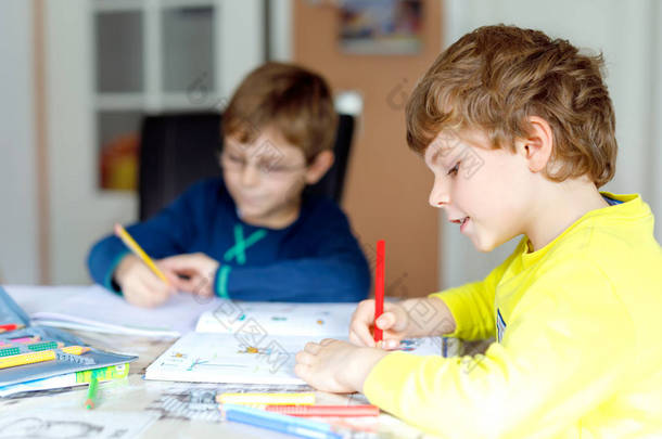 两个孩子在家做家庭作业。小孩子们在室内用五颜六色的铅笔<strong>写字</strong>。小学和教育。兄弟姐妹和最好的朋友学习.