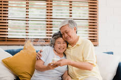 亚洲老年夫妇男子拿着蛋糕庆祝妻子的生日在家里的客厅。日本夫妇在家里一起享受爱情时刻。生活方式 老年家庭在家的概念.