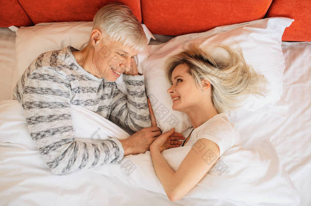 成熟的爱情夫妻睡觉前在卧室里互相看着对方。成年夫妻躺在床上, 幸福的关系 