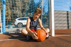 高加索青少年男孩街头篮球运动员与球在室外城市篮球场
