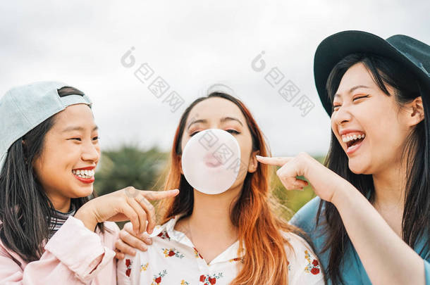 快乐的亚洲朋友有乐趣咀嚼泡泡糖户外-年轻人一起玩耍和笑-友谊, 千禧一代和青年生活方式的概念