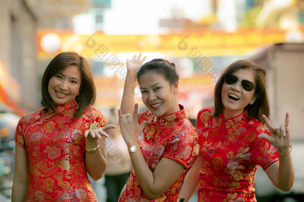 一群穿着中国传统服装的亚洲女人, 穿着牙齿的笑脸、幸福的情感和手的符号我爱你 