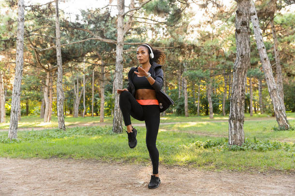 在绿色公园运动的精力充沛的 2 0多岁身穿黑色运动服的女子形象