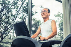 老人在健身中心的跑步机上锻炼。成熟健康的生活方式.