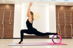 穿着运动服的年轻女子带着瑜伽轮在健身房做瑜伽练习。伸展与健康的生活方式.