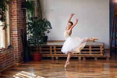 年轻的芭蕾舞演员穿着白色的图图练习舞蹈动作。舞蹈学校的年轻女孩穿着芭蕾礼服.