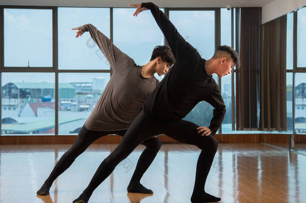 两个亚洲人同时在工作室的巨大窗户附近跳<strong>舞美</strong>丽的当代舞蹈