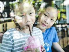 快乐的亚洲孩子享受他们的饮料在咖啡店, 生活方式的概念.