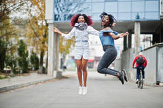 两个有吸引力的非洲裔美国女人跳对现代多层建筑.