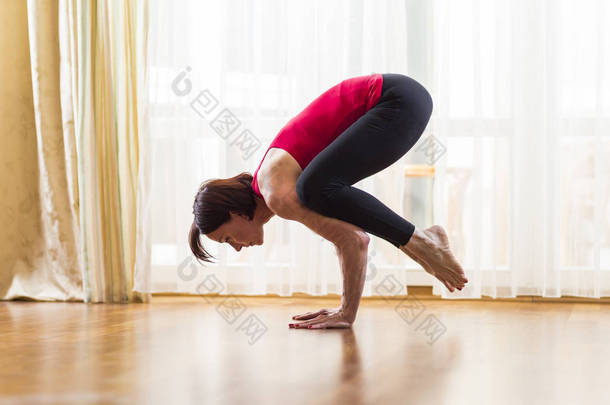 瑜伽概念。在明亮的下午, 白种人妇女在室内练习瑜伽练习。在孤独冥想期间坐在巴卡萨纳的姿势里。