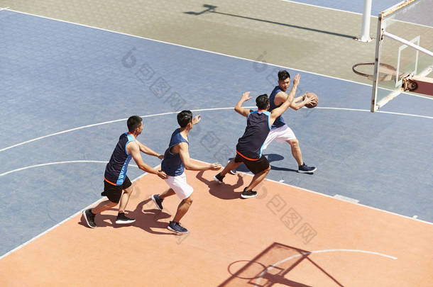 年轻的亚洲男子篮球运动员在户外赛场上玩游戏.