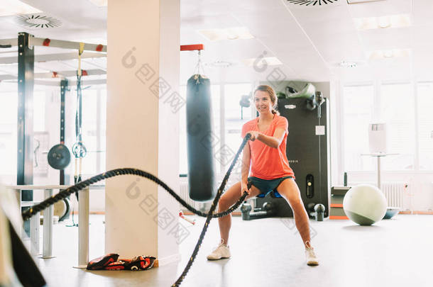 年轻的健康的妇女行使与绳索在健身房