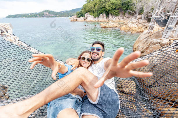 年轻美丽快乐快乐微笑有趣的夫妇男人和女人最好的朋友在吊床上的假期聊天和享受生活