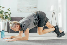运动员在运动服训练中的侧视图在瑜伽垫在家里