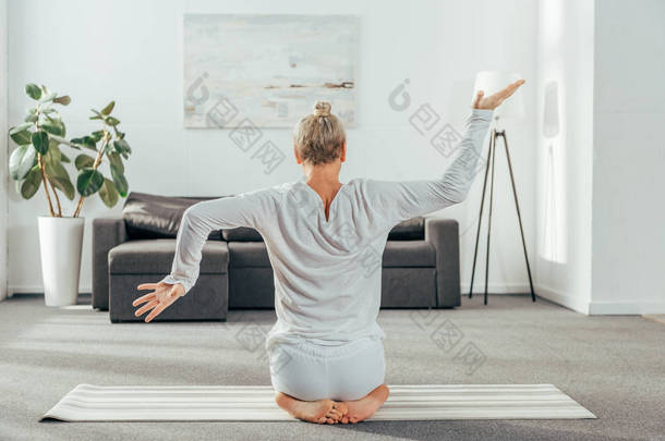 在运动服上练习瑜伽的成人男子的背视图在家里