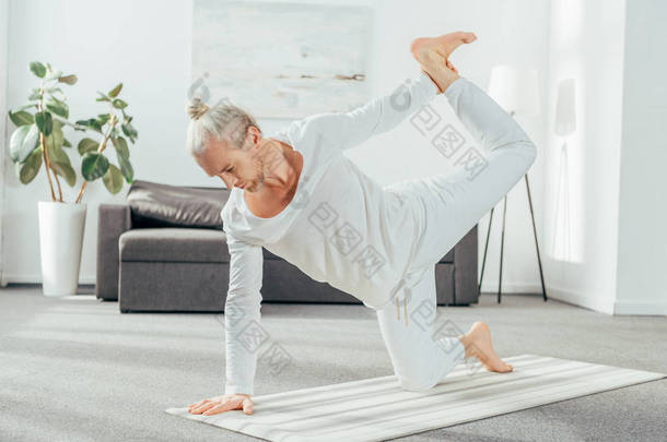 赤脚成年男子在家里练习<strong>瑜伽</strong>的全长视图