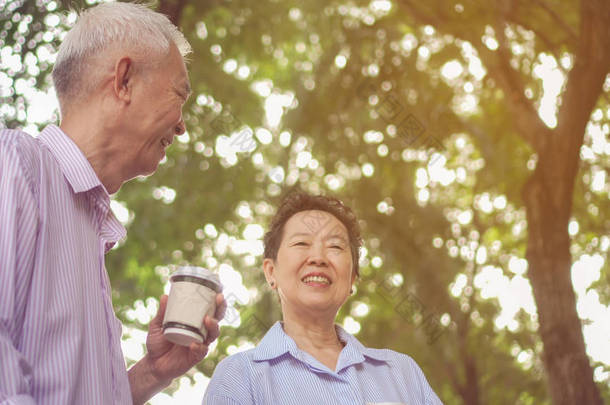 愉快的亚洲老人夫妇早晨散步在绿色城市喝咖啡和谈话