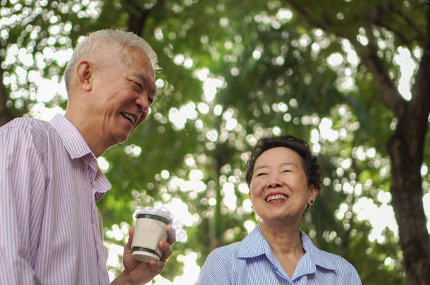 愉快的亚洲老人夫妇早晨散步在<strong>绿色城市</strong>喝咖啡和谈话