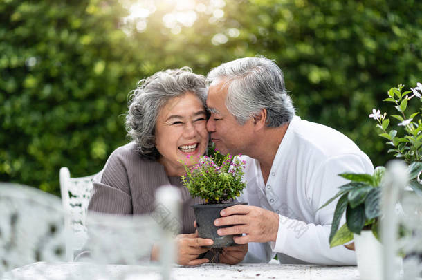 亚洲老人亲吻妻子的肖像。老夫妇享受与种植花在<strong>花园里</strong>。退休.