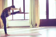 瑜伽平衡练习。瑜伽教练显示平衡姿势。美丽的运动优雅的妇女在健身房