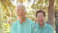 亚洲老年夫妇一起在绿色自然公园的背景下欢笑