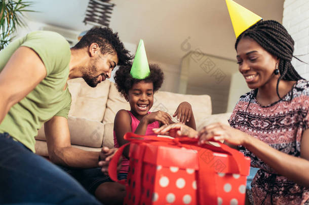 家庭快乐的黑人家庭。非洲裔美国人的父亲, 母亲和孩子庆祝生日, 在聚会上玩得开心。送女儿礼物的年轻妇女