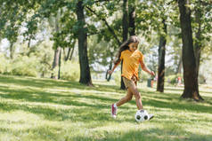 美丽的快乐的孩子玩足球在公园 