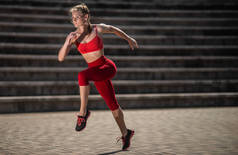 年轻健身妇女在体育场在夏天奔跑。健康生活方式的概念