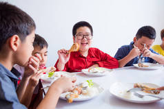 亚洲小男孩在学校食堂与朋友共进午餐时微笑着